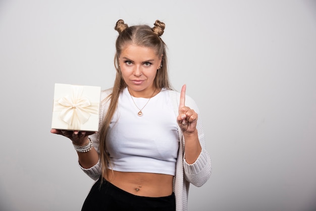 Portret van een vrouw met een geschenkdoos die aandacht geeft.