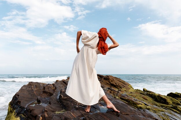 Portret van een vrouw op het strand die haar gezicht bedekt met een sluier