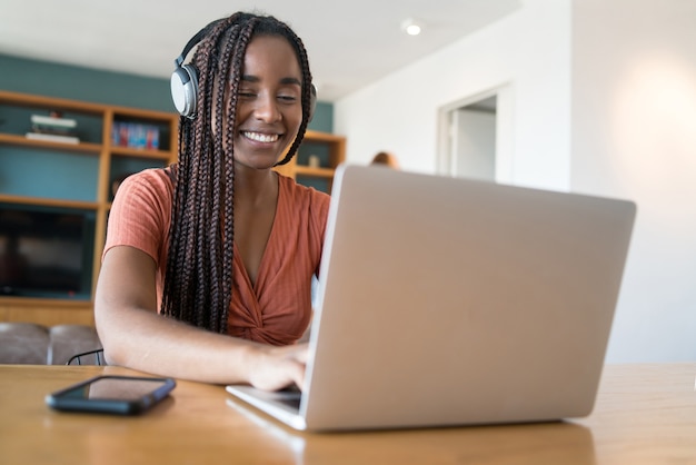 Portret van een vrouw tijdens een videogesprek met laptop en koptelefoon terwijl ze thuis werkt. kantoor aan huis concept. nieuwe normale levensstijl.