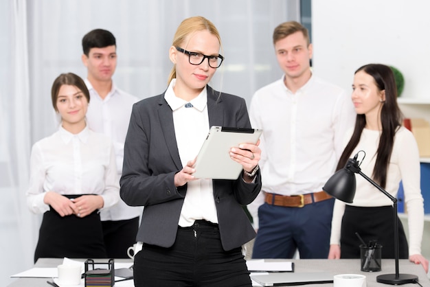 Portret van een vrouwelijke manager die digitale tablet houdt die ter beschikking zich voor collega bevindt