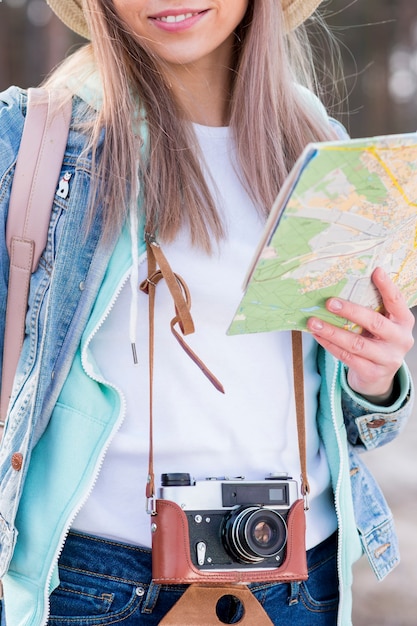 Portret van een vrouwelijke reiziger die uitstekende camera en kaart houdt