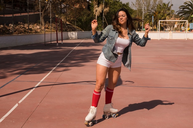 Portret van een vrouwelijke skater die op een openluchthof schaatst