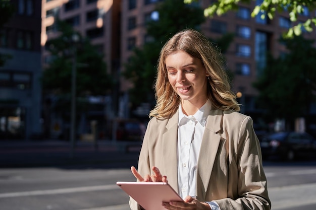 Portret van een zakelijke vrouw die haar digitale tablet gebruikt en op straat werkt en naar kantoor gaat