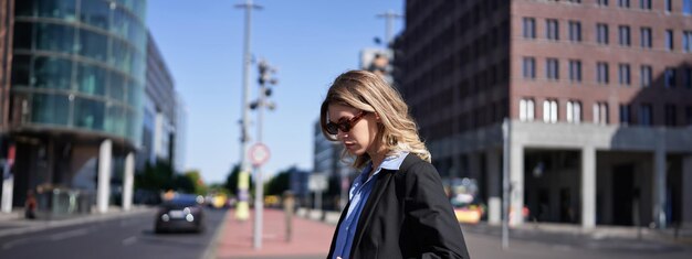 Portret van een zakelijke vrouw in pak en zonnebril die op straat staat en er zelfverzekerd en ontspannen uitziet