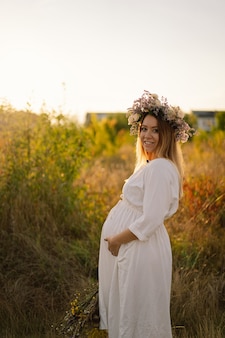 Portret van een zwangere vrouw een mooie jonge zwangere vrouw in een witte jurk loopt in het veld