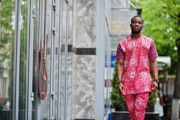 Portret van een zwarte jonge man die Afrikaanse traditionele rode kleurrijke kleding draagt