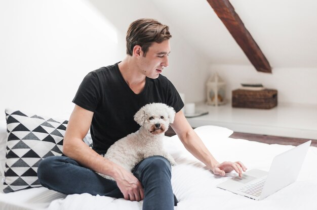Portret van eigenaar met zijn vriendschappelijke hond die laptop thuis met behulp van