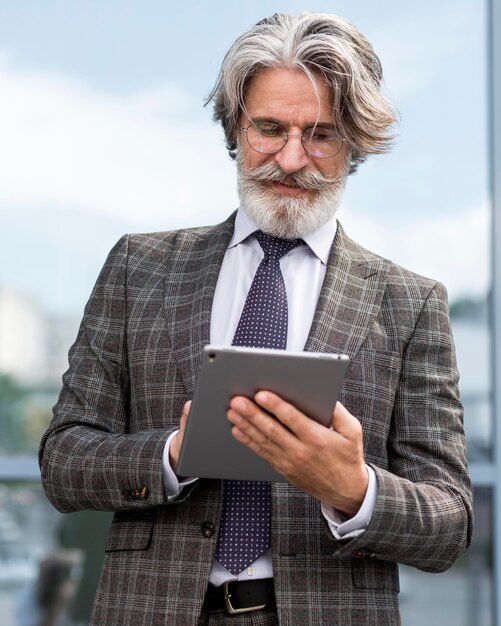 Portret van elegante volwassen mannelijke doorbladert tablet