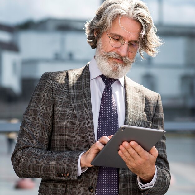 Portret van elegante volwassen mannelijke doorbladert tablet