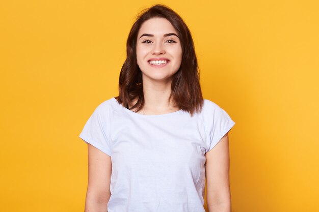 Portret van emotionele goed uitziende blanke vrouw lacht terwijl u rechtstreeks naar de camera kijkt