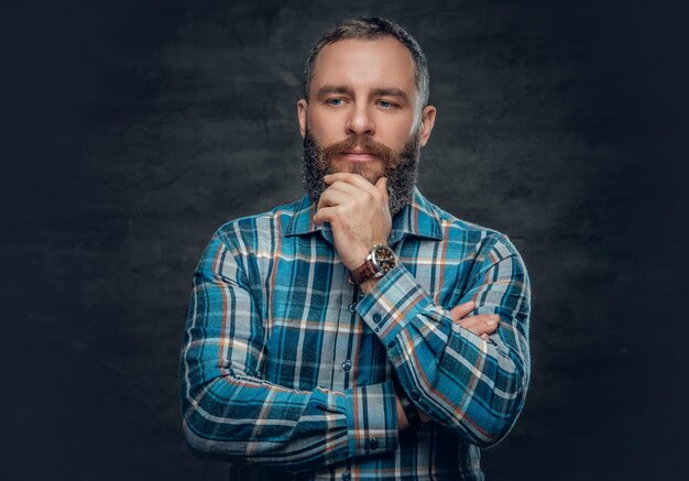 Portret van ernstige middelbare leeftijd bebaarde man gekleed in geruite flanellen overhemd over grijze achtergrond.