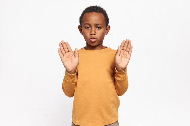 Portret van ernstige zelfverzekerde Afro-Amerikaanse schooljongen in sweatshirt reiken zijn handen met palmen open stop gebaar maken