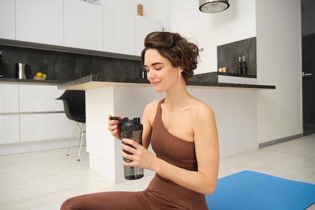 Portret van fitness vrouw jonge sportvrouw drinkt thuis water uit de fles na training