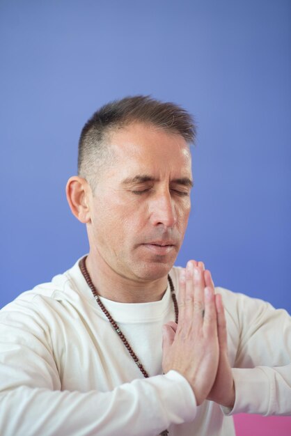 Portret van geabsorbeerde man bidden. Man in casual kleding met gesloten ogen. Spiritualiteit, gezondheidsconcept
