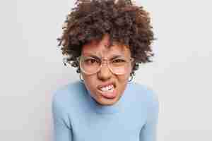 Gratis foto portret van geïrriteerde jonge vrouw klemt tanden vol haat kijkt boos draagt optische bril en blauwe trui geïsoleerd op witte achtergrond onder druk gezet wordt gestrest of pissig.