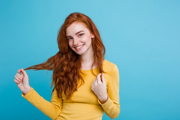 Portret van gelukkig gember rood haar meisje met sproeten glimlachend kijken naar camera. Pastel blauwe achtergrond. Ruimte kopiëren.