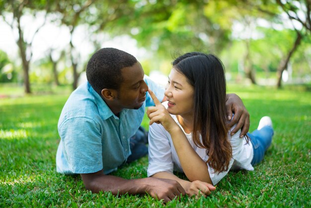 Portret van gelukkig jong paar dat op gras en het flirten ligt.