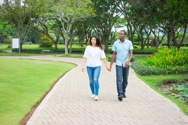 Portret van gelukkig multi-etnisch paar die samen in park lopen.
