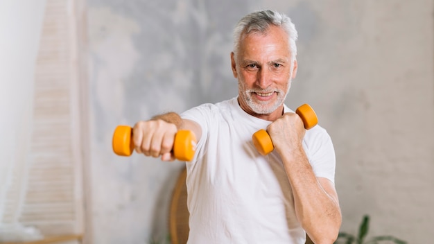 Portret van gelukkig senior man tillen gewichten