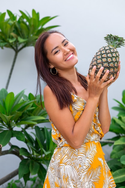 Portret van gelukkige Aziatische glimlachende vrouw in gele de greepananas van de de zomerkleding