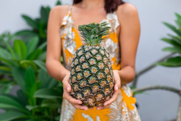 Portret van gelukkige Aziatische glimlachende vrouw in gele de greepananas van de de zomerkleding