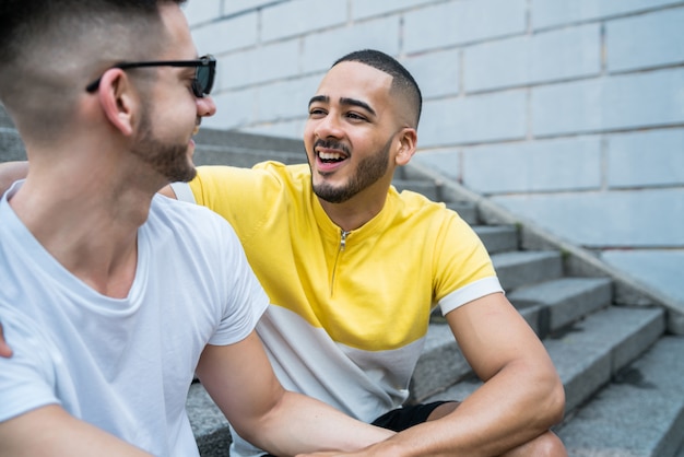 Portret van gelukkige homo paar tijd samen doorbrengen zittend op trappen buitenshuis.