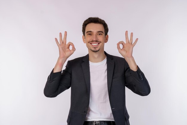 Portret van gelukkige jonge knappe zakenman die ok teken met hand en vingers over witte achtergrond doet