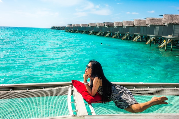 Portret van gelukkige jonge vrouw bij mooie water villa op eiland maldiven. reizen en vakantie. buiten schot