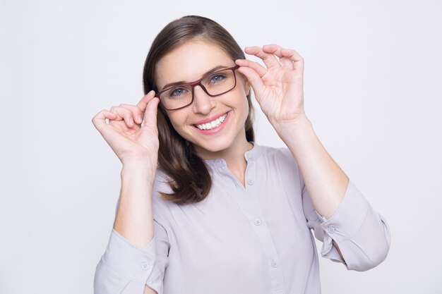 Portret van gelukkige jonge vrouw die probeert op brillen