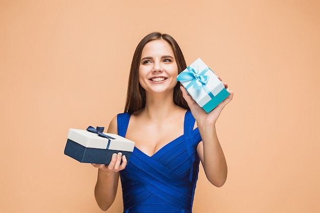 Portret van gelukkige jonge vrouw met geschenken geïsoleerd op bruine achtergrond met gelukkige emoties