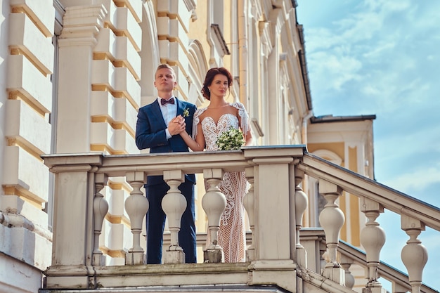 Portret van gelukkige jonggehuwden omarmen terwijl ze poseren op de trappen van het prachtige oude paleis.