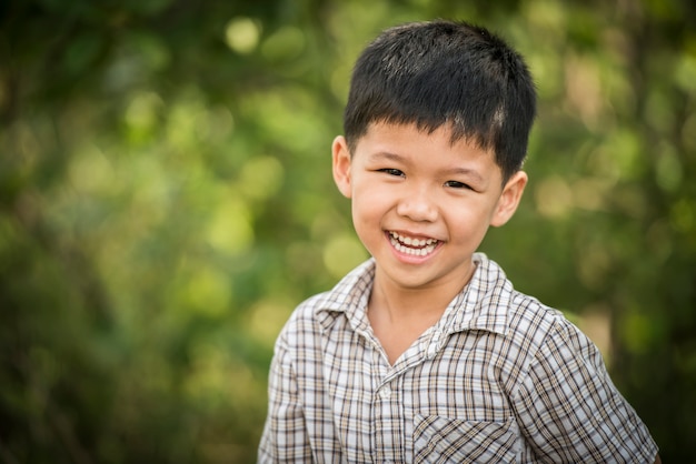 Portret van gelukkige kleine jongen lachen terwijl hij in het park speelt.