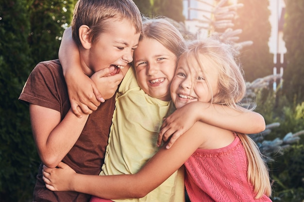 Portret van gelukkige kleine vrienden die plezier hebben op de werf. Drie schattige kleine vrienden knuffelen en spelen.