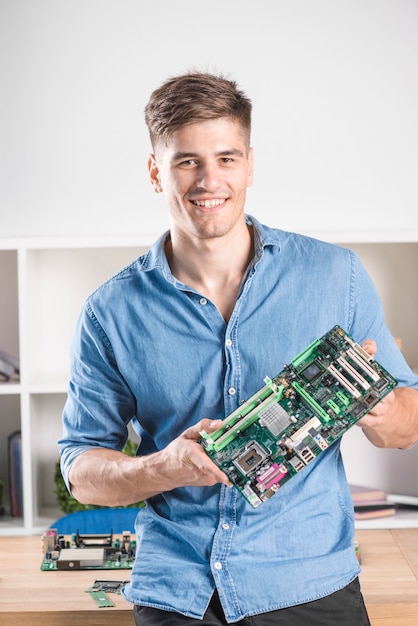 Portret van gelukkige mannelijke technicus die modern computermotherboard houdt