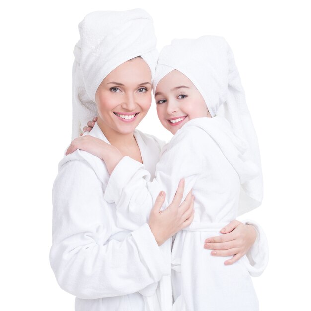 Portret van gelukkige moeder en jonge dochter in witte peignoir en geïsoleerde handdoek. Gelukkig gezin mensen concept.