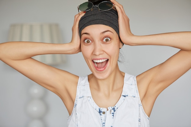 Portret van gelukkige mooie jonge vrouw in grijze hoofdband op zoek opgewonden close-up