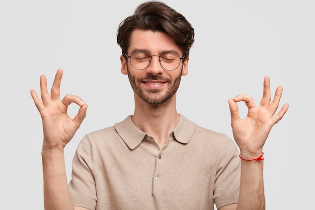 Portret van gelukkige ongeschoren jonge mannelijke hipster maakt ok teken