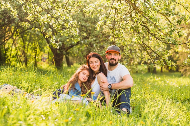 Gratis foto portret van gelukkige paar zittend op groen gras in het park