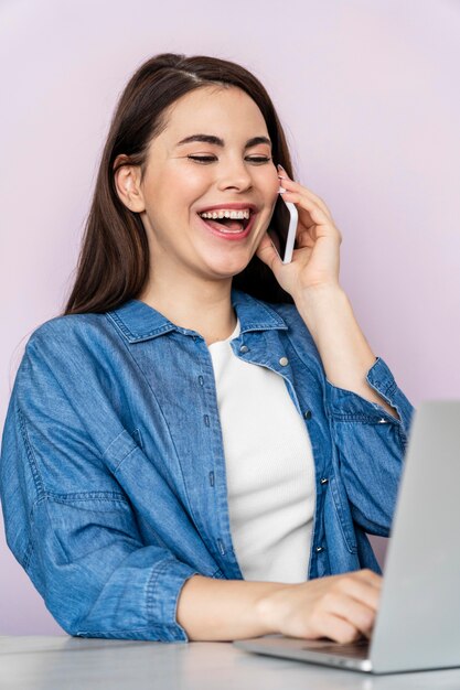 Portret van gelukkige vrouw praten aan de telefoon en laptop gebruikt