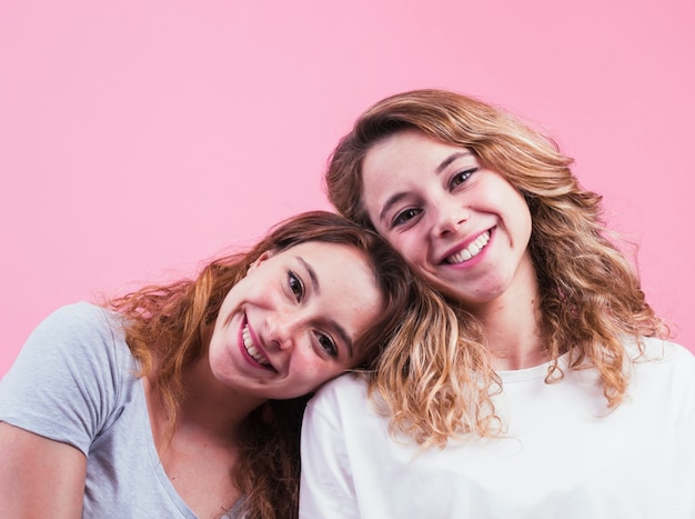 Gratis foto portret van gelukkige zuster tegen roze achtergrond