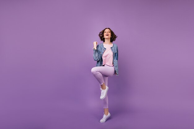 Portret van gemiddelde lengte van tevreden verbazende vrouw in witte schoenen. Blanke meisje draagt vrijetijdskleding dansen.