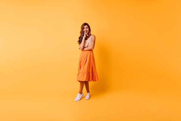 Portret van gemiddelde lengte van vrolijke gembervrouw. Romantisch Kaukasisch meisje in oranje kleren