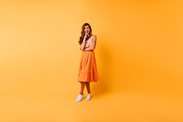 Portret van gemiddelde lengte van vrolijke gembervrouw. Romantisch Kaukasisch meisje in oranje kleren
