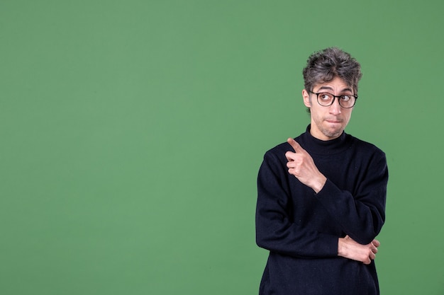 Gratis foto portret van geniale man in studio-opname wijzend op groene muur