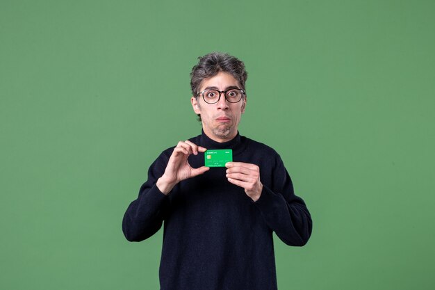 Portret van geniale man met groene creditcard op groene muur