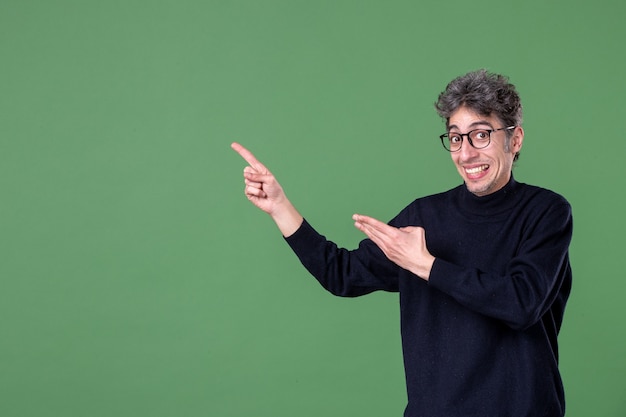 Portret van geniale man terloops gekleed in studio-opname op groene muur