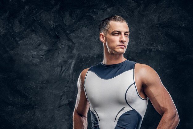 Portret van gespierde knappe man in wetsuit en met een wolk van talk rond over donkere achtergrond.