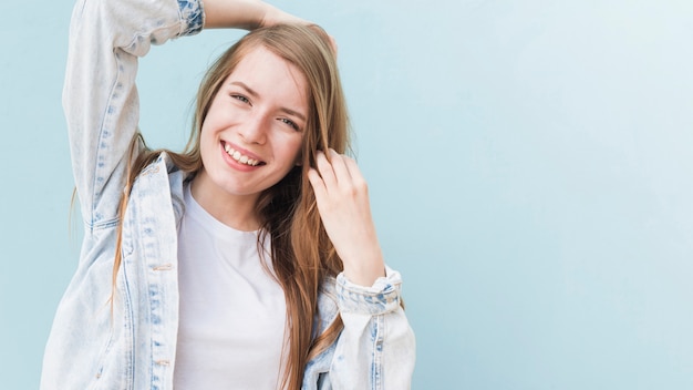 Gratis foto portret van glimlachende aantrekkelijke vrouw op blauwe muur