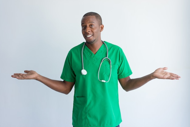 Portret van glimlachende Afrikaanse Amerikaanse arts die schouders ophalen.