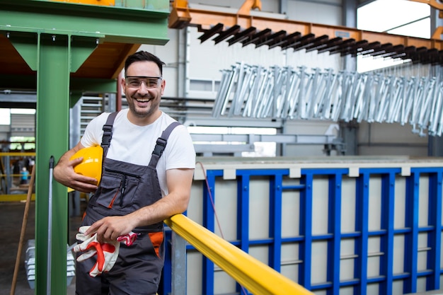 Portret van glimlachende man fabrieksarbeider permanent in industriële productiehal